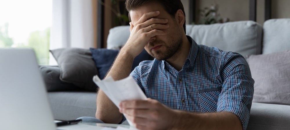 Medical Liens in Illinois: How Much of Your Settlement Can a Hospital Take? 1 Man sitting on a couch with his hand over his eyes while holding a medical bill